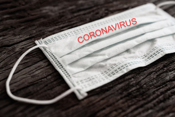 Dramatic atmosphere with surgical mask with coronavirus text written on it. 2019-nCoV virus infection in Wuhan city. Covid-19 ( SARS-CoV-2 ) spread around the world. Impact of pandemic virus.
