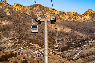 The cable car is going up the mountain in the winter, beautiful sunlight.