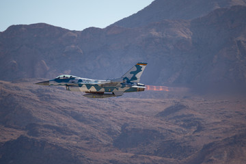 F-16 Fighting Falcon in the Aggressor color scheme  against the Nevada hills, with missiles on the...