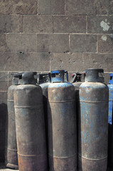 Group of old gas cylinders against a gray block wall