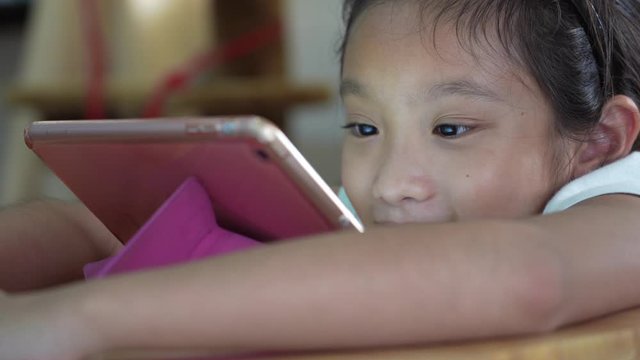 Asian kid girl watching computer tablet screen, handheld shot
