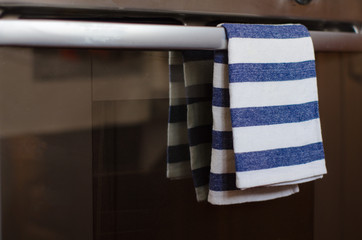 A blue-and-white-striped kitchen towel hangs on the handle of the oven door. Selective focus.