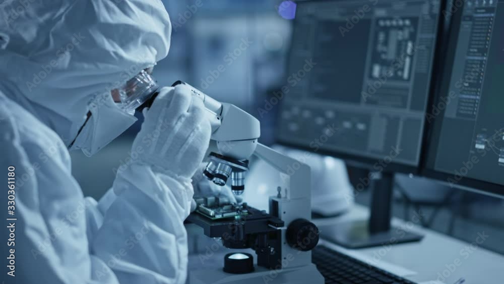 Poster research factory cleanroom: engineer / scientist wearing coverall and uses microscope to inspect sam
