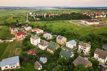 Fototapeta na wymiar Aerial landscape of small town or village with rows of residential homes and green trees.