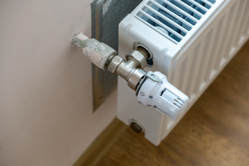 Closeup of heating radiator valve for comfortable temperature regulation on metal radiator on inrerior wall.