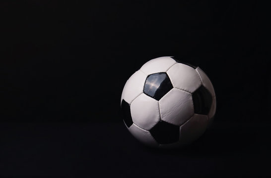 Classic football ball isolated on a black background with copy space for publicity and advertising. Real photo, traditional soccer ball symbol over dark wall.