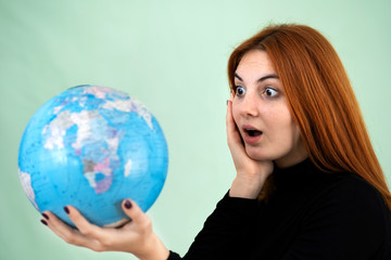 Portrait of a sad worried young woman holding geographic globe of the world in her hands. Travel destination and planet protection concept.