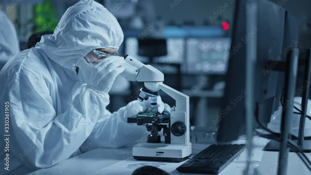 Poster research factory cleanroom: engineer / scientist wearing coverall, gloves uses microscope to inspect