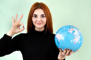 Portrait of a happy young woman holding geographic globe of the world in her hands. Travel destination and planet protection concept.