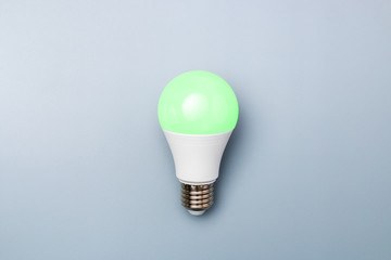 switched on led bulb with green light on grey background with copy space for advert. business idea concept