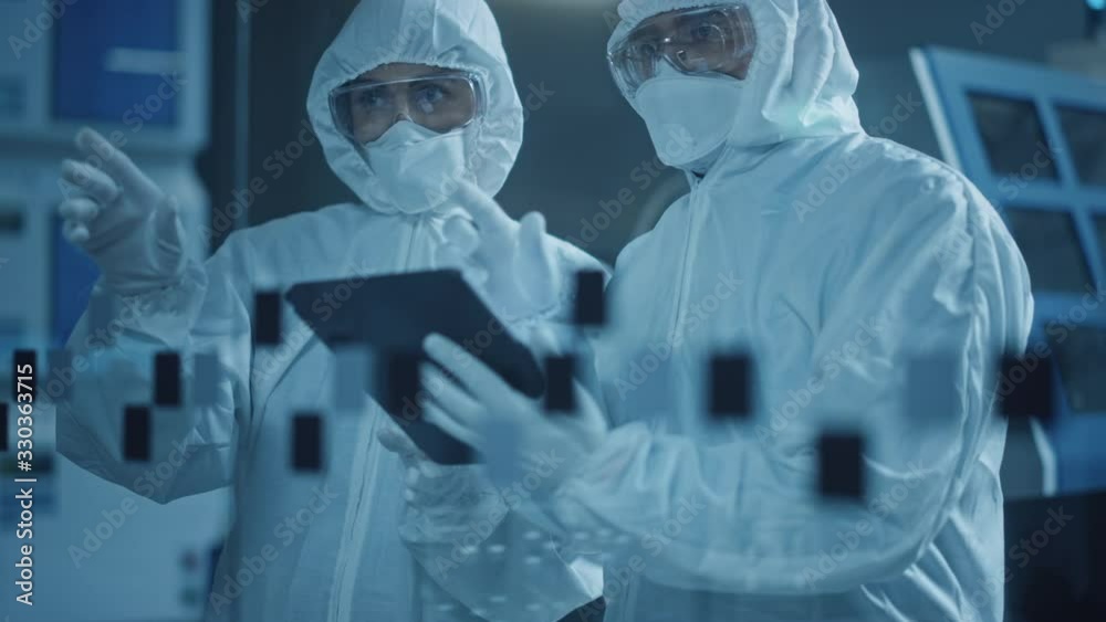 Poster factory cleanroom: engineer and scientist wearing coveralls, standing in workshop talk and use table