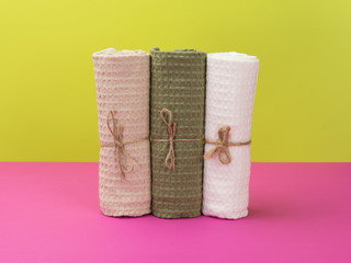 Three towels in eco-style on a pink and green background.