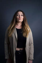 Attractive light haired female rounds lips, wears yellow turtleneck sweater, looks directly into camera, expresses her satisfaction, isolated over gray background. People, body language conceptâ€ 