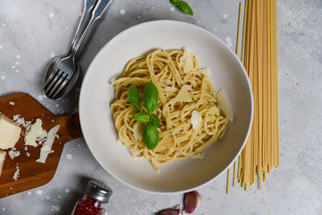 Spaghetti pasta with parmesan cheese and basil in a white plate on a light background top view. gluten free spaghetti recipe homemade pasta. classic Italian cuisine. selective focus
