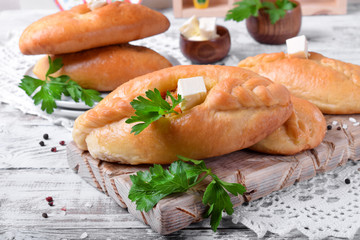 Rasstegai pie of yeast dough with meat filling on white wooden table. Traditional meal of Russian cuisine