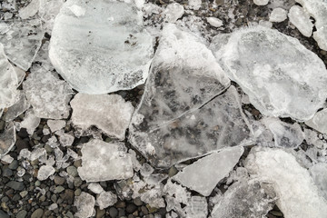 Close-up of cracked pieces of ice lying on grey pebbles