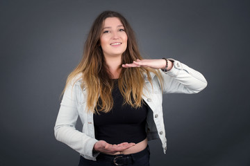 Blonde European woman over isolated background gesturing with hands showing big and large size sign, measure symbol. Smiling looking at the camera. Measuring concept.