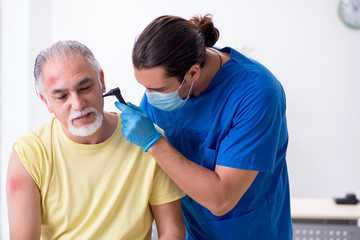 Obraz premium Injured old man visiting young male doctor traumatologist