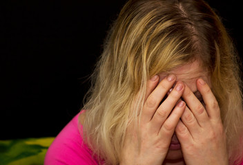 Fototapeta premium woman who has experienced domestic violence, cries with her hands covered in her face. Black background