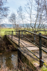 Fototapeta premium Little iron bridge across the little river and a green meadow
