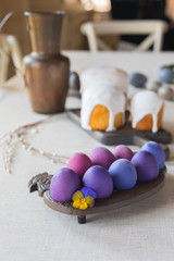 Naturally dyed Easter hen's eggs with a vioet flower on linen background