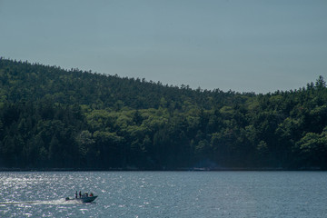 Boat speedings across water with tree covered hills in the backgorund