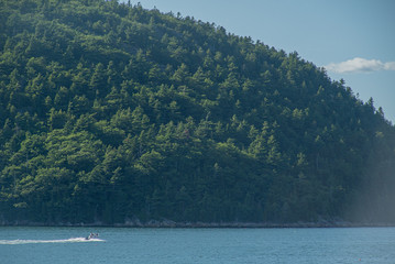 Speed boat on lake with tree covered mountain in the background