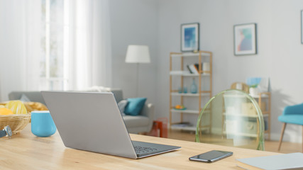 Shot of a Modern Silver Laptop on a Wooden Table at Home. Smartphone Lies on a Table Next to the Computer.