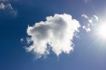 White cloud and bright sun against blue sky background.