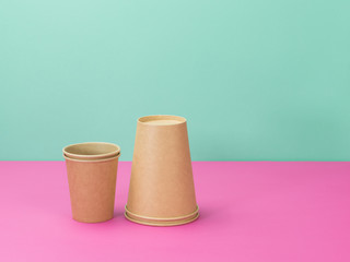 Disposable paper cups on a pink and turquoise background.