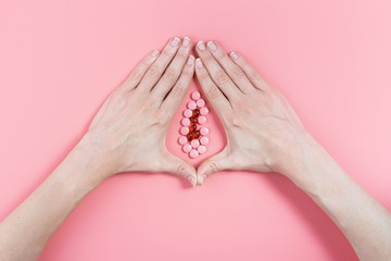 abstract image of female genital organs from hands and pills. concept of women's health and the...