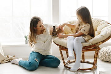 A nice cute girl and her beautiful mother enjoy sunny day. Family playing together with a rabbit in...