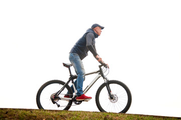 Obraz premium the young man goes by bicycle against the background of the white sky in the park