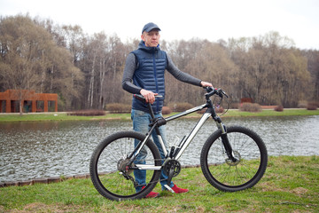 the young man with bicycle in the park in the spring
