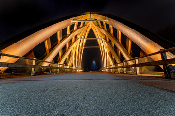 Wooden traffic bridge in the evening with illuminated curved lines and high-up perspective