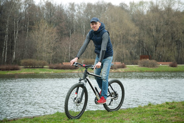 Obraz premium the young man goes by bicycle in the park in the spring