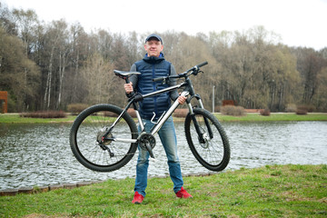 Fototapeta premium the young man keeps the bicycle in the park in the spring