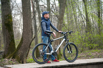 Fototapeta na wymiar the young man with bicycle in the park in the spring