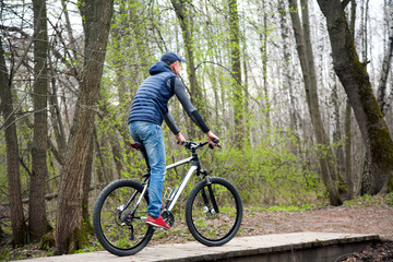 Fototapeta na wymiar the young man goes by bicycle in the park in the spring