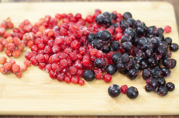 frozen berries. raspberries, black and red currants. on a wooden table