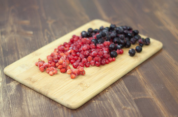 frozen berries. raspberries, black and red currants. on a wooden table