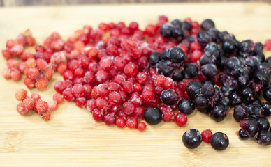 frozen berries. raspberries, black and red currants. on a wooden table