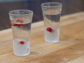 ice-cold vodka glasses with raspberries and currants on a wooden stand