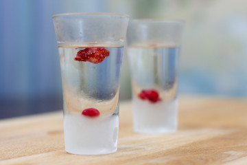 ice-cold vodka glasses with raspberries and currants on a wooden stand