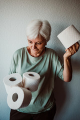 .Middle-aged woman hoarding a lot of toilet paper. Madness caused by the coronavirus health crisis.