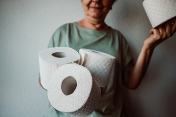 .Middle-aged woman hoarding a lot of toilet paper. Madness caused by the coronavirus health crisis.