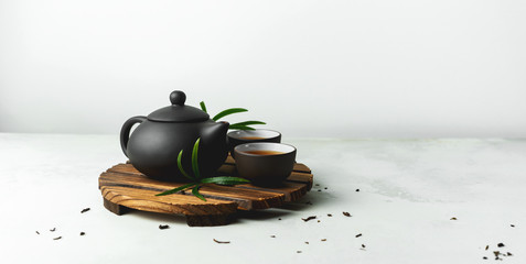 Asian food background with a tea set, cups, and teapot with free space for text on white stone background.
