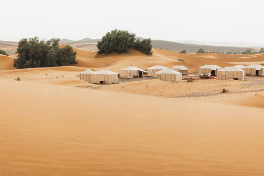 Contemporary Luxury Glamping Camp In Morocco Sahara Desert. Sand Dunes Around. Many White Modern Eco Tents.