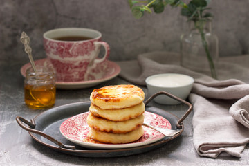 Cottage cheese pancakes, homemade syrniki with honey and sour cream.