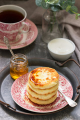 Cottage cheese pancakes, homemade syrniki with honey and sour cream.